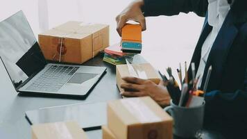 Emprendedora de pequeñas empresas o mujer asiática independiente que usa una computadora portátil con caja, joven mujer asiática de éxito con su mano levantada, caja de embalaje de marketing en línea y entrega, concepto de pyme. video