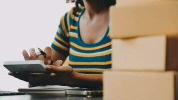 Emprendedora de pequeñas empresas o mujer asiática independiente que usa una computadora portátil con caja, joven mujer asiática de éxito con su mano levantada, caja de embalaje de marketing en línea y entrega, concepto de pyme. video