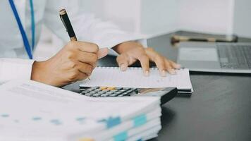 Asian Business woman using calculator and laptop for doing math finance on an office desk, tax, report, accounting, statistics, and analytical research concept video