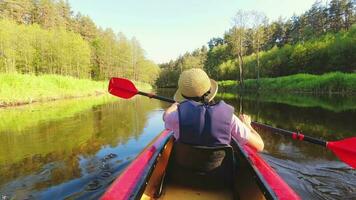 Close up kayaking woman without life-vest in river.POV of woman kayaking in beautiful green forest. Aquatic refreshing water sports in hot summer. Meditative calm relaxing activity video