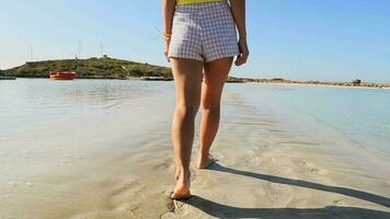 cerca arriba rastreo ver mujer descalzo caminar pasos en blanco arena en nisi playa. cristalino Mediterráneo aguas Chipre relajante fiesta destino. mejor playa en Chipre video