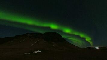 aurora boreal sobre anel estrada rodovia com carros passagem sair luz trilhas. aurora Caçando noite enquanto viagem dentro Islândia. Pare sobre Caçando auroras dentro sulista Islândia video