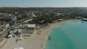 Ayia Napa, Cyprus - 15th april, 2023 - aerial fly over Luxury hotel buildings with pools by beach with island greenery panorama.White sand most famous in Cyprus - Nissi beach video