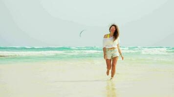 The girl walks along the beach, white sand and blue sea. Kiteboarding. video