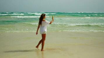 uma menina leva uma selfie em uma lindo praia, poses com uma Smartphone video