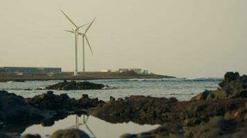 Wind Generator auf das Ufer von das Bucht, reflektiert im das Wasser video