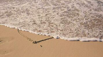 a coração é pintado em a areia e lavado longe de a onda video