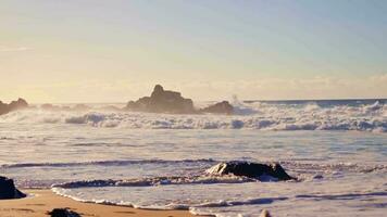 Sea waves crash against the coastal rocks on the sandy beach. video