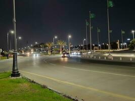 Jeddah, Saudi Arabia, June 2023 - A beautiful view of Saudi Arabian flags flying at Jeddah Corniche Road intersection at night. photo