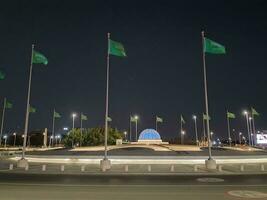 Jeddah, Saudi Arabia, June 2023 - A beautiful view of Saudi Arabian flags flying at Jeddah Corniche Road intersection at night. photo