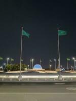 Jeddah, Saudi Arabia, June 2023 - A beautiful view of Saudi Arabian flags flying at Jeddah Corniche Road intersection at night. photo