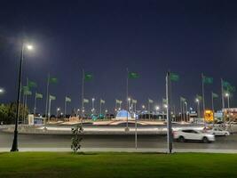 Jeddah, Saudi Arabia, June 2023 - A beautiful view of Saudi Arabian flags flying at Jeddah Corniche Road intersection at night. photo