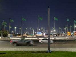 Jeddah, Saudi Arabia, June 2023 - A beautiful view of Saudi Arabian flags flying at Jeddah Corniche Road intersection at night. photo