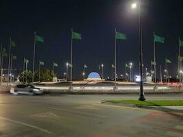 Jeddah, Saudi Arabia, June 2023 - A beautiful view of Saudi Arabian flags flying at Jeddah Corniche Road intersection at night. photo