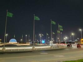 Jeddah, Saudi Arabia, June 2023 - A beautiful view of Saudi Arabian flags flying at Jeddah Corniche Road intersection at night. photo