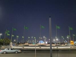 Jeddah, Saudi Arabia, June 2023 - A beautiful view of Saudi Arabian flags flying at Jeddah Corniche Road intersection at night. photo