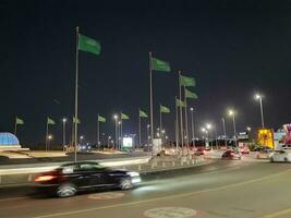 Jeddah, Saudi Arabia, June 2023 - A beautiful view of Saudi Arabian flags flying at Jeddah Corniche Road intersection at night. photo