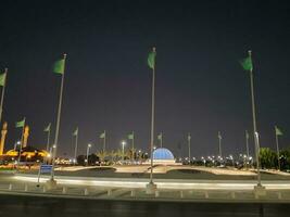 Jeddah, Saudi Arabia, June 2023 - A beautiful view of Saudi Arabian flags flying at Jeddah Corniche Road intersection at night. photo