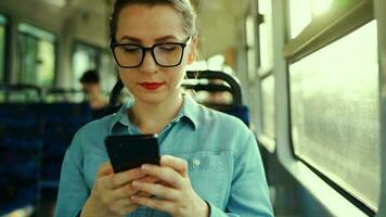 offentlig transport. kvinna i glasögon i spårvagn använder sig av smartphone. långsam rörelse video