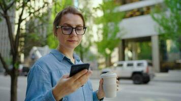 Caucasian woman in glasses walking around the city and using smartphone video