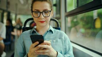 Public transport. Woman in glasses in tram using smartphone. video