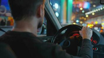 hombre conducción coche mediante el calles de noche ciudad. video