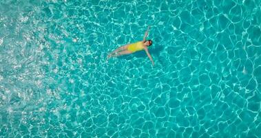 parte superior abajo ver de un mujer en azul traje de baño acostado en su espalda en el piscina. video