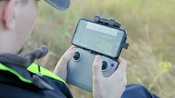 drone operator hands using remote control with sticks and cellphone as monitor at daylight video