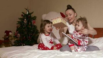 Young mother shows wooden box to her small children in the bed video