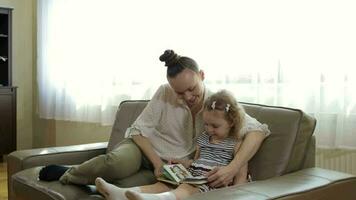 joven madre y su pequeño hija son leyendo poemas para desarrollando multa motor de un niño. video