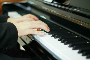 Hands of a man in a black suit and white shirt playing music from the piano. Soft focus photo of the musicians of a wedding ceremony at the church.