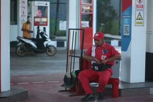 un masculino gas estación asistente es sentado relajado contando dinero.magelang,indonesia.junio 10, 2023 foto