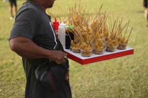 Sempolan is a kind of fried food made from tapioca flour and eggs. It is sold on a wooden tray. photo