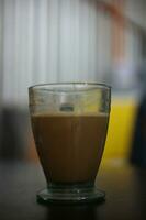 cappuccino served in small size clear glass coffee cup over blurred background selective focus. photo