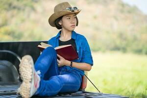 Woman wear hat and reading the book on pickup truck photo
