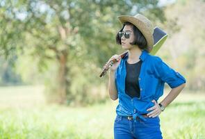 mujer usa sombrero y lleva su guitarra en el campo de hierba foto