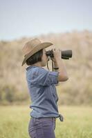 Woman wear hat and hold binocular in grass field photo