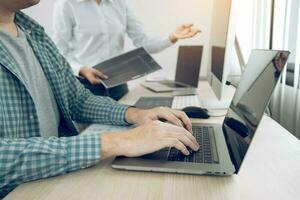 Two partnerships developing programming and coding technologies working on laptop and analyzing together. photo