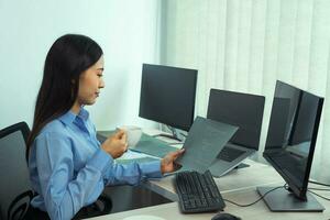 Asian woman was drinking coffee in the early morning while contemplating the program and code on the computer screen. photo