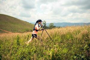 Young women active trail running across a meadow on a grassy trail high in the mountains in the afternoon with trekking pole photo