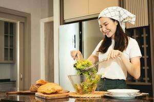 ama de casa asiática preparando verduras frescas para hacer ensalada en el mostrador de la cocina de casa. foto