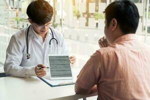 Asian doctor talking the patient at clinic while using the tablet explaining the patient condition and the treatment result. photo