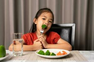 Asian little girl eating healthy vegetables with relish. photo