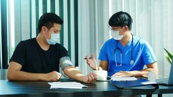 Asian doctor is using a patient's blood pressure monitor at the time of his annual check-up and explains his blood pressure. photo