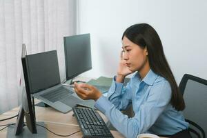 Concentrated asian woman brainstorming while coding data on desktop PC while working on computer codes in the office. photo