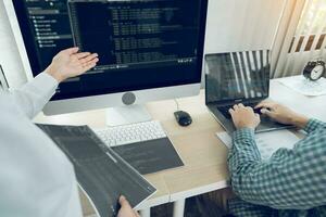 Two software developers are analyzing together about the code written into the program on the computer in office room. photo