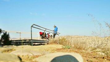 caucásico masculino ciclista en escénico punto de vista utilizando inteligente teléfono para social medios de comunicación conectar al aire libre en campo, navegar en remoto áreas, tiene perdido, captura señal en alto montañas video