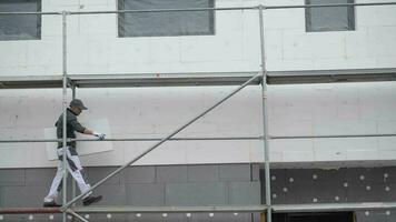 Caucasian Worker on a Scaffolding Working with External Building Insulation. video