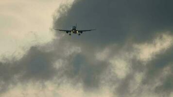 passageiro avião aproximação e mosca baixo sobre pista, frente visualizar. cênico nublado céu com raios solares em pano de fundo video