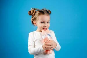 retrato de un pequeño contento niña de eslavo apariencia Bebiendo un cóctel de bayas. sitio para texto foto